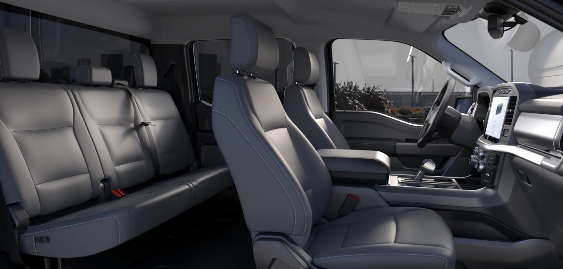 A roomy cabin of the F-150 Lightning is shown with gray leather seating. Two seats up front are on either side of a wide console, a touchscreen interface is in the dash, and a bench seat for three is in the back