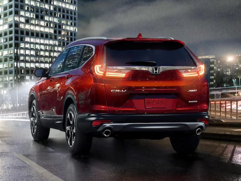 Back side Exterior of a red 2019 Honda CR-V driving down a city street at night