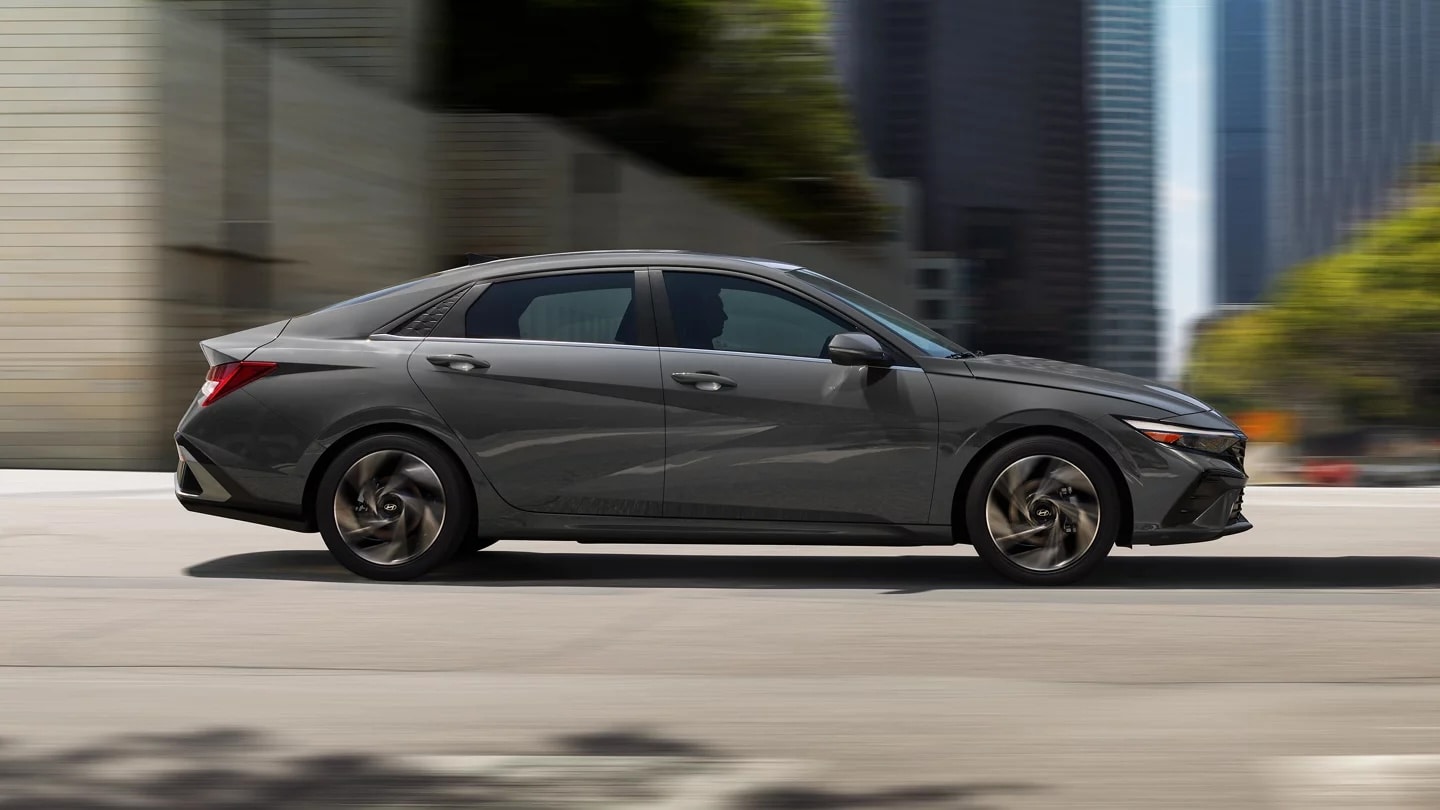 Gray 2026 Hyundai Elantra Hybrid driving through the city, side profile in motion
