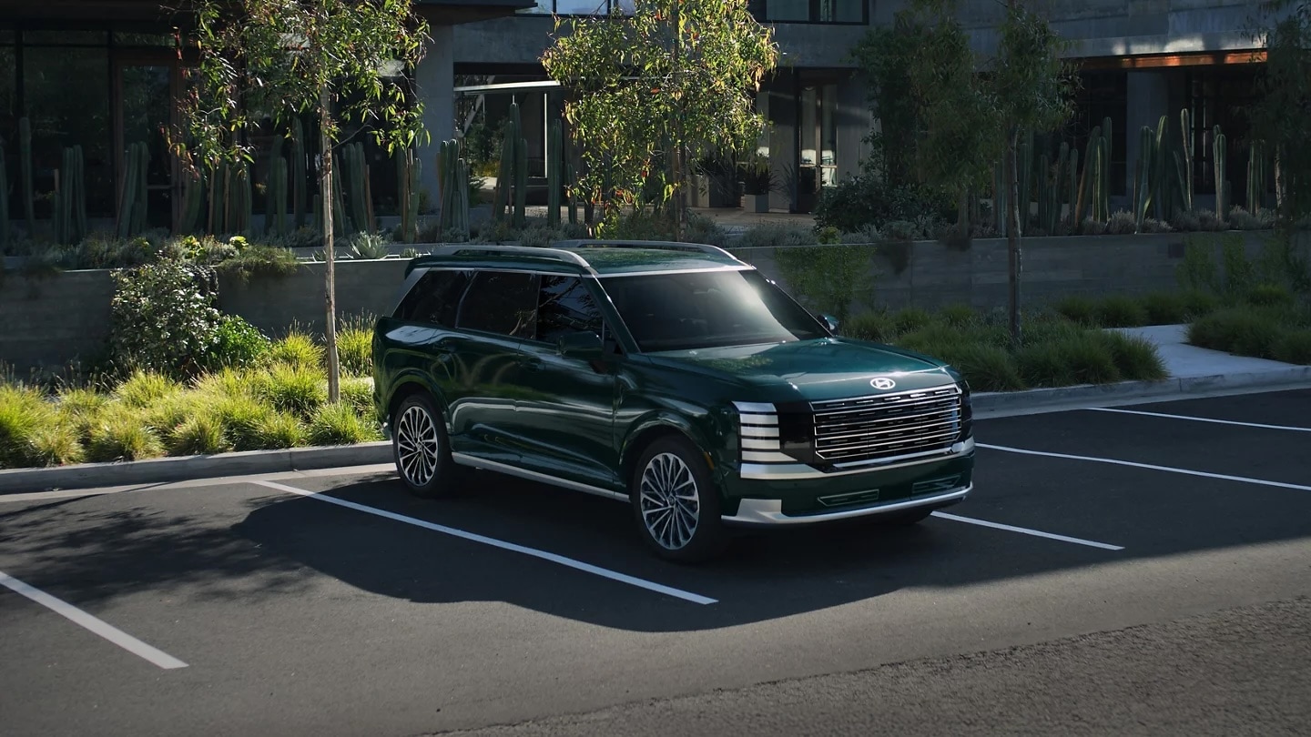 Green 2027 Hyundai Palisade Hybrid three-row SUV parked outside a modern building, front three-quarter view