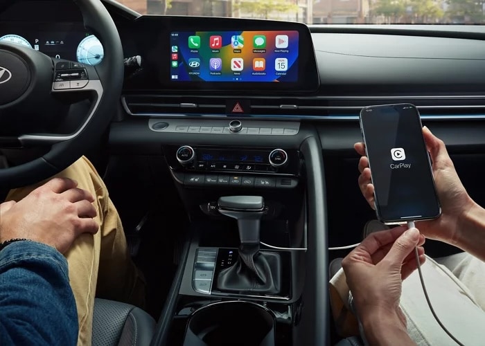Apple CarPlay on the 2026 Hyundai Elantra Hybrid touchscreen with a passenger holding a smartphone