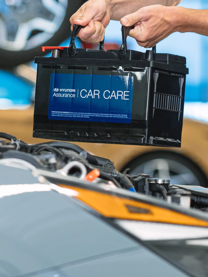 Technician installing a new Hyundai Car Care battery during routine maintenance