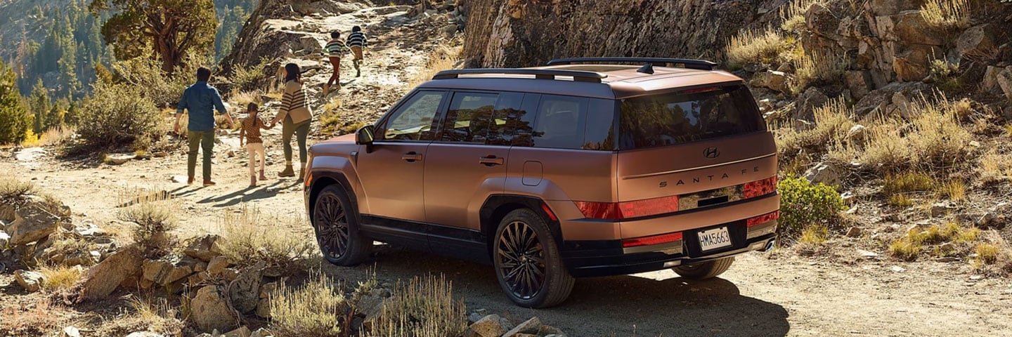 2027-hyundai-santa-fe-final.jpg Rear profile of the 2027 Hyundai Santa Fe Calligraphy in Earthy Brass Matte parked near a hiking trail in Colorado Springs