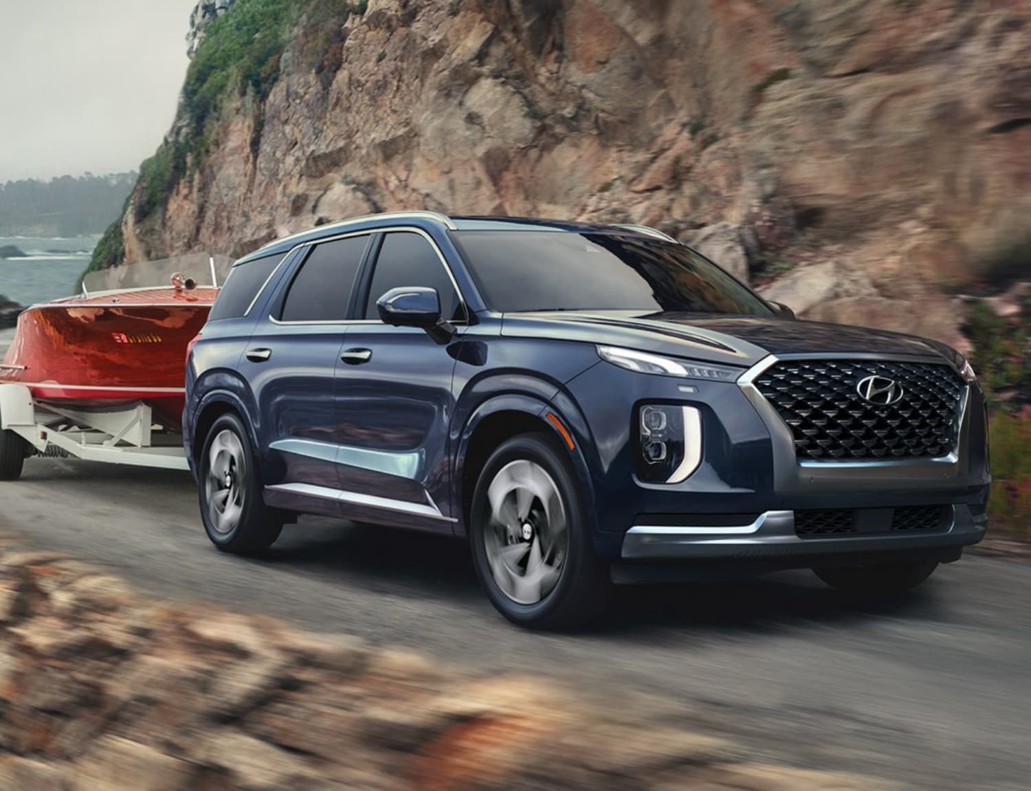 New 2021 Hyunda Palisade Calligraphy towing a boat around a mountain side highway