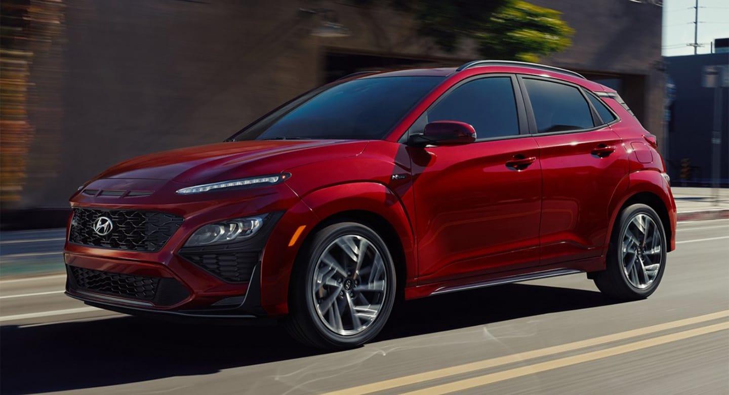 A profile view of a red 2022 Hyundai Kona as it speeds down a road