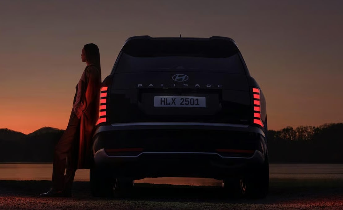 Driver standing next to their 2026 Hyundai Palisade as sunset