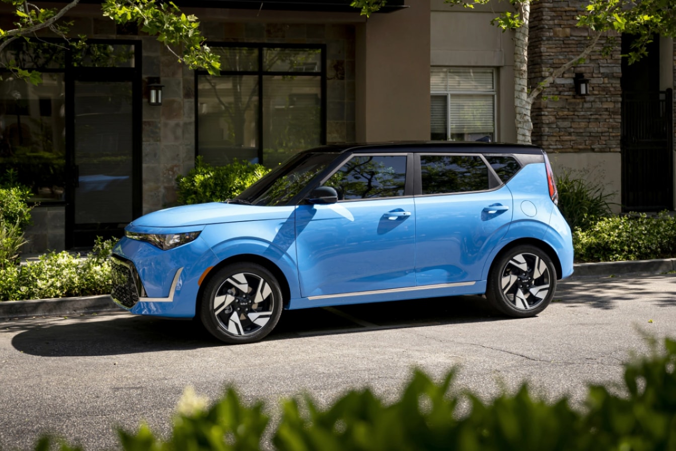 A profile view of a blue 2023 Kia Soul parked on a city street