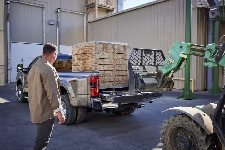 A heavy bundle being loading into the back of the 2023 Ford F-350 by a forklift.