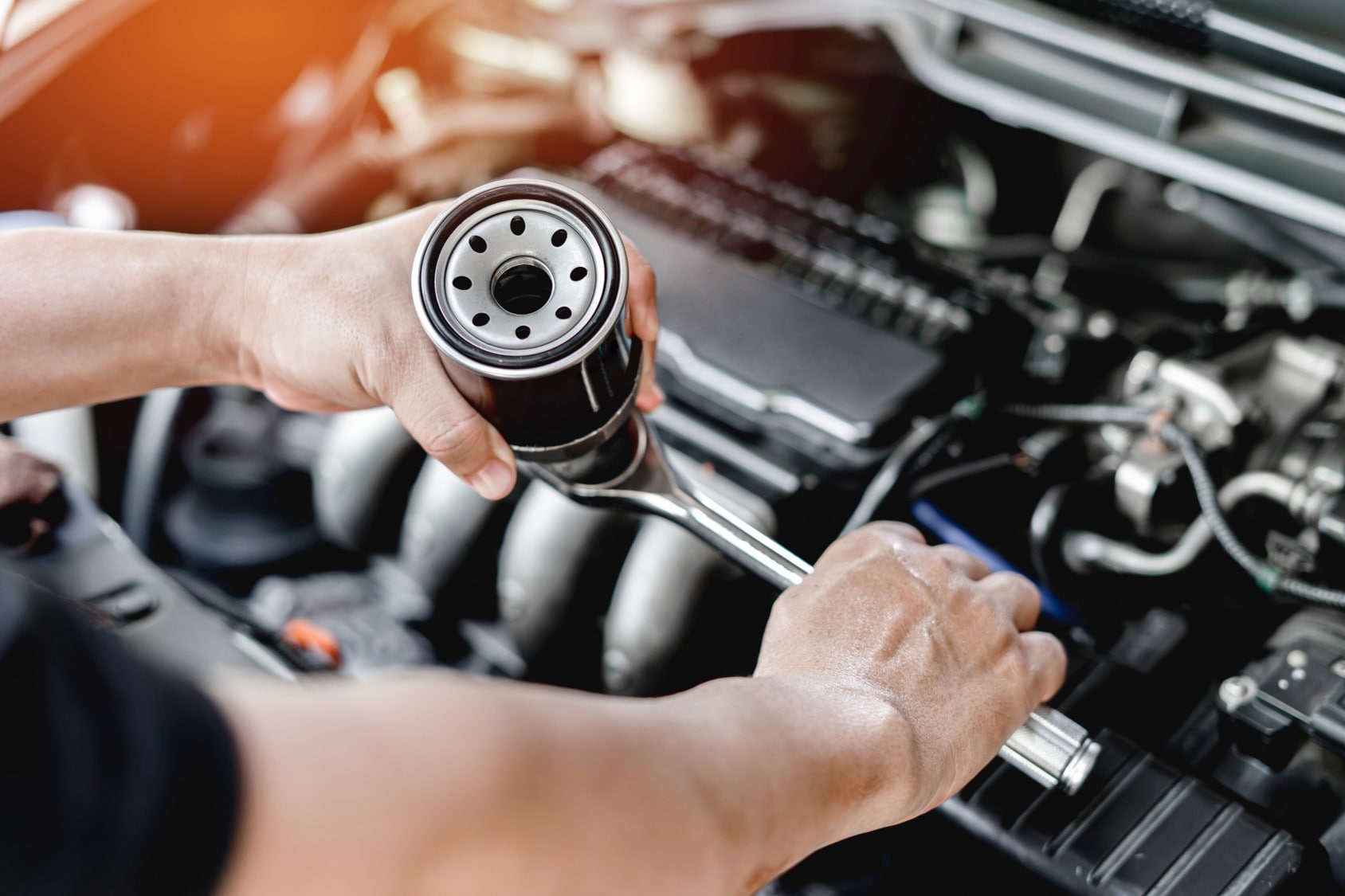 A closeup of a man's hands as he changes the oil in a car
