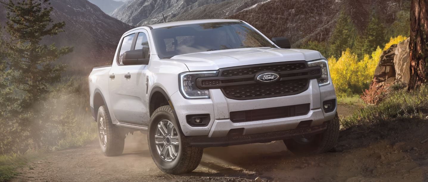 A white Ford Ranger driving down a road.