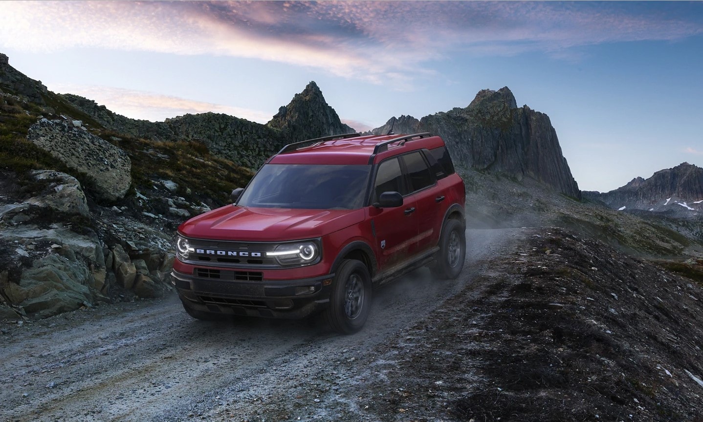 A red Ford Bronco Sport driving at dusk in the mountains