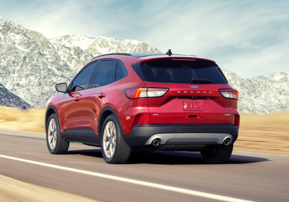 A new 2020 Ford Escape driving in-motion down an open road into the mountains