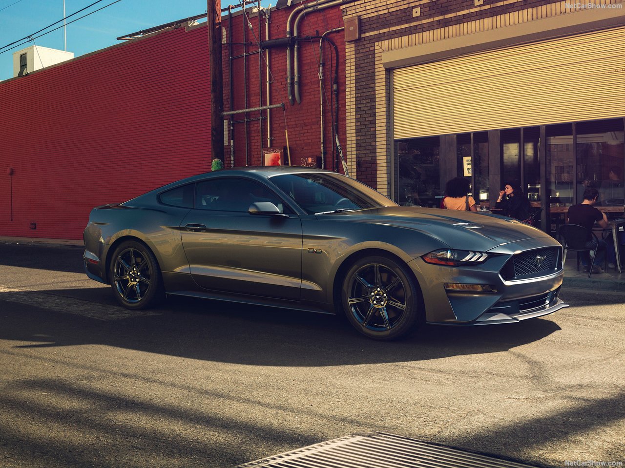 A grey 2018 Ford Mustang parked outside of a shop.