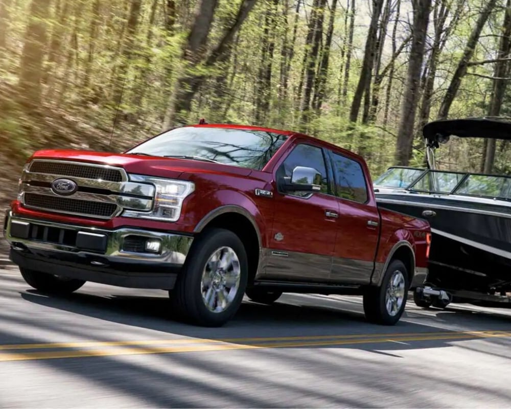 Ruby Red 2019 Ford F-150 towing a large boat down a highway