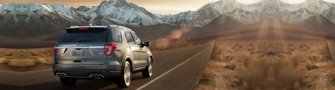 Rear angle of a 2019 Ford Explorer as the SUV drives down an open road heading to the mountains
