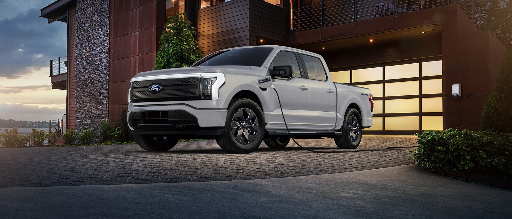 A white Ford F-150 Lightning parked outside a brick home.