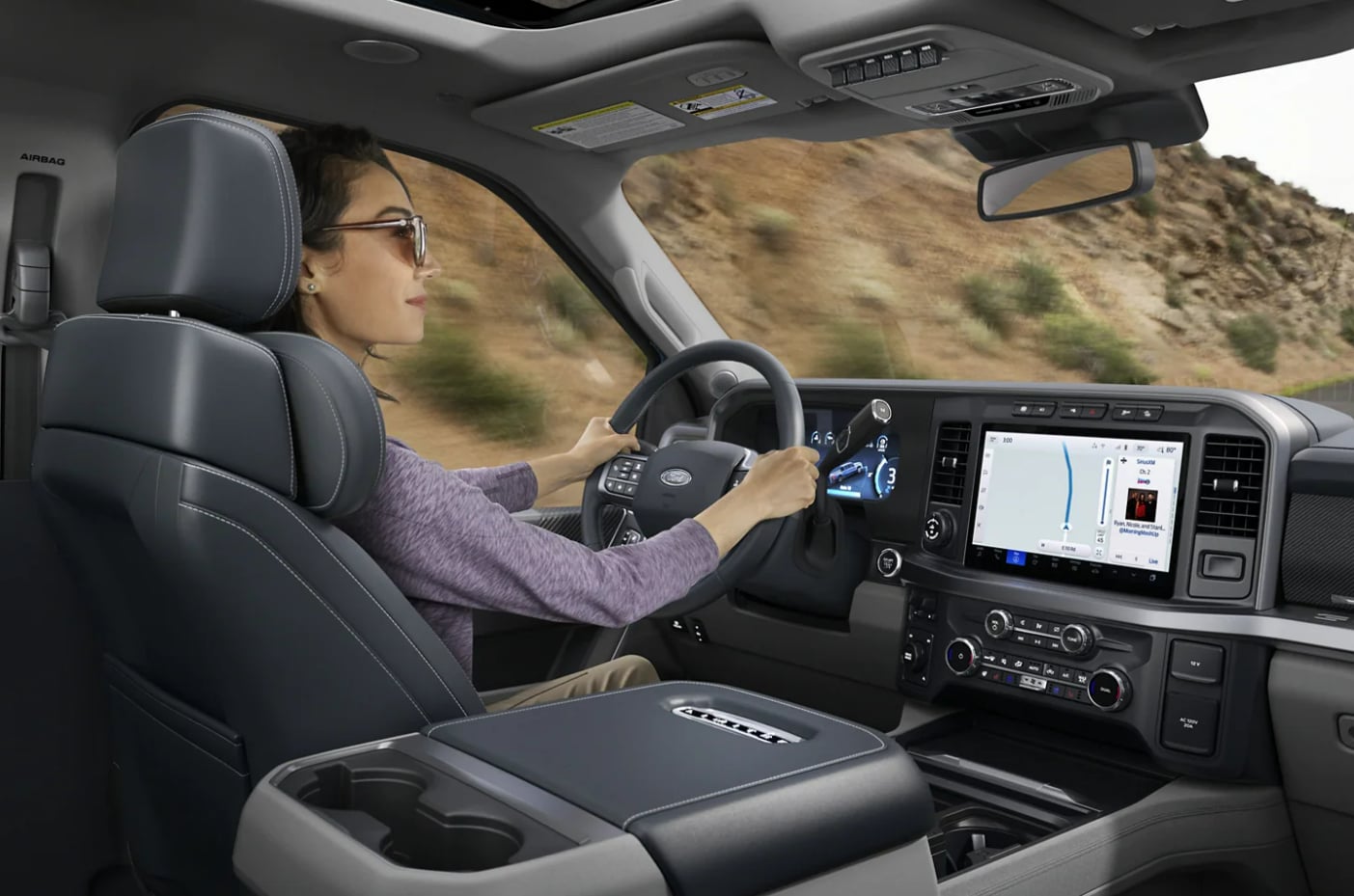 A woman sits in the drivers seat with both hands on the wheel in a 2023 Ford Super Duty