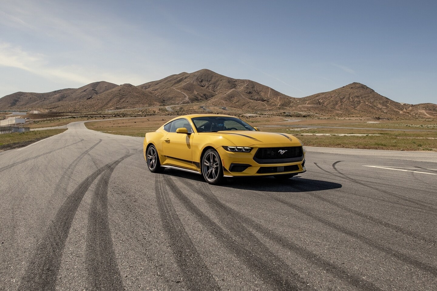 A yellow Ford Mustang parked on a racetrack.