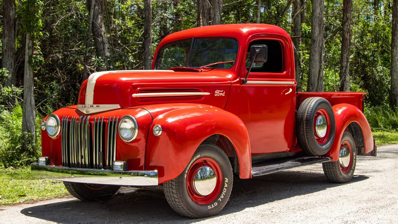 A red first generation Ford F-Series Truck parked.