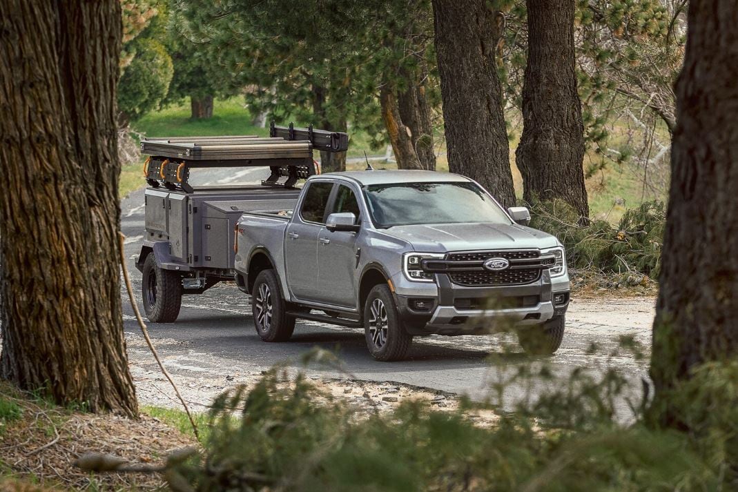A 2024 Ford Ranger pulling a small pull behind camping setup through a forest.