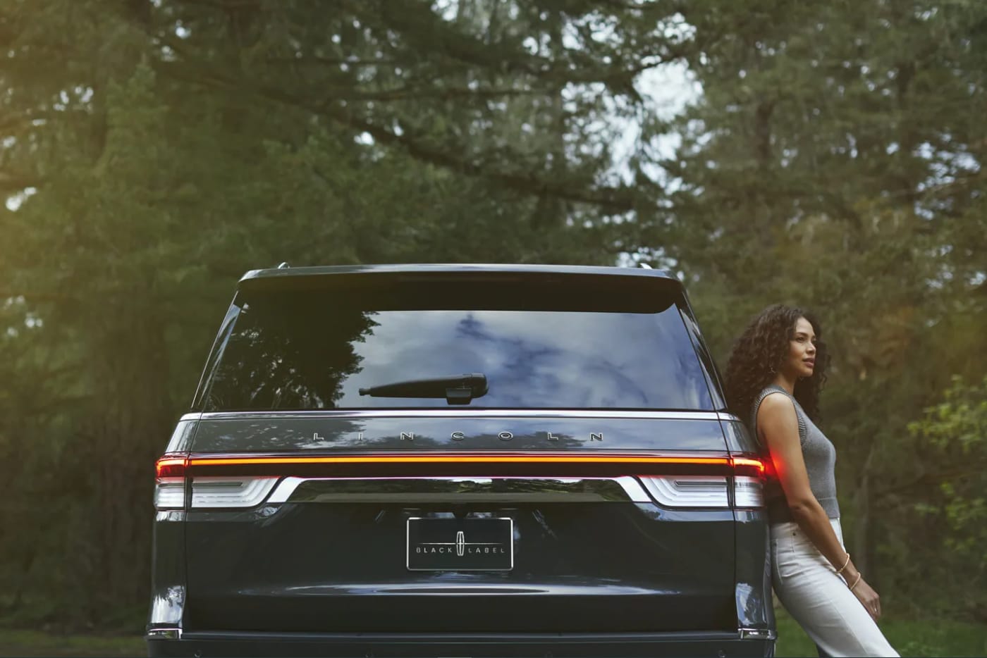 A woman leans on the side of a black 2022 Lincoln Navigator