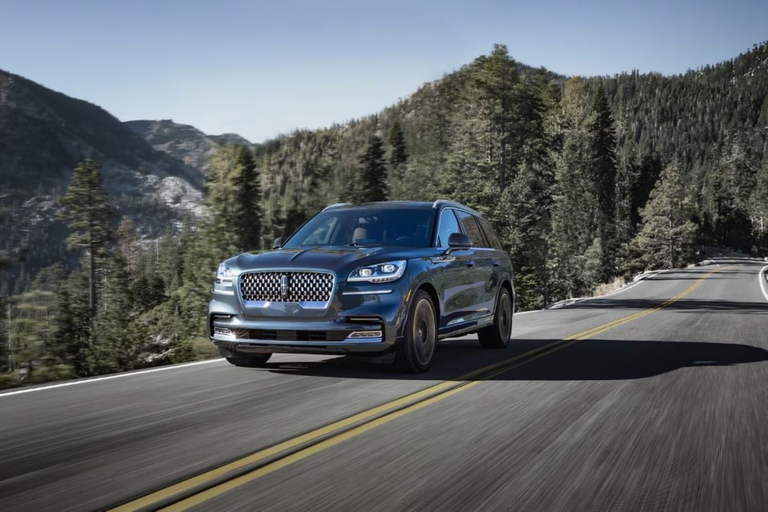 A Lincoln driving through a snowy mountain pass.