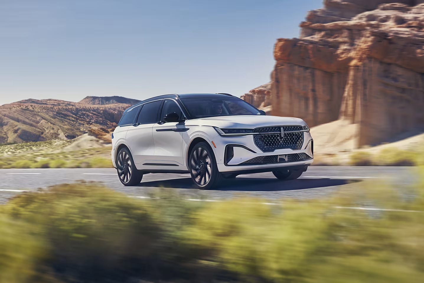A white 2025 Nautilus driving through a desert road