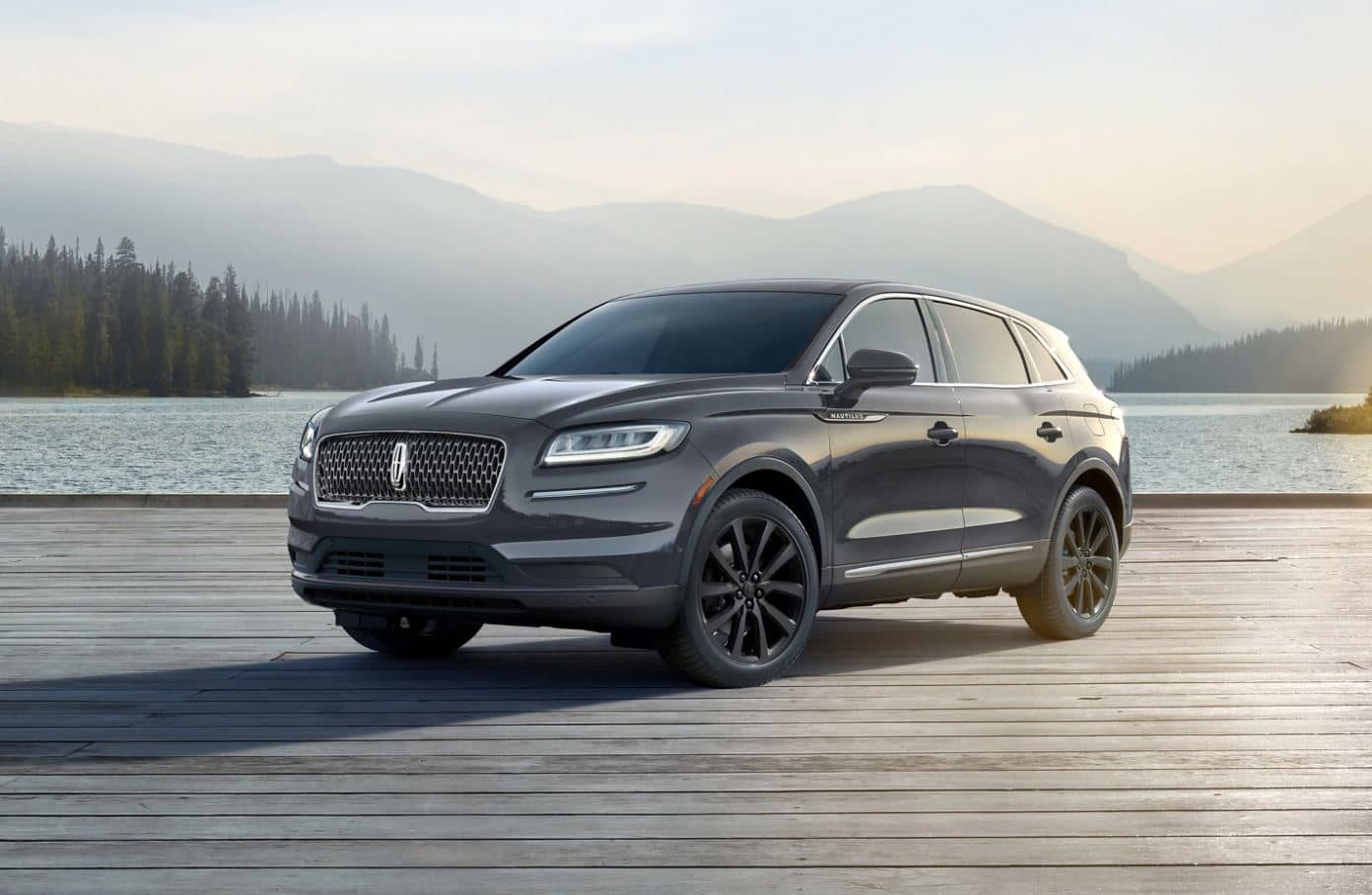 a grey 2022 Lincoln Nautilus parked on a dock with a lake and mountain range in the background