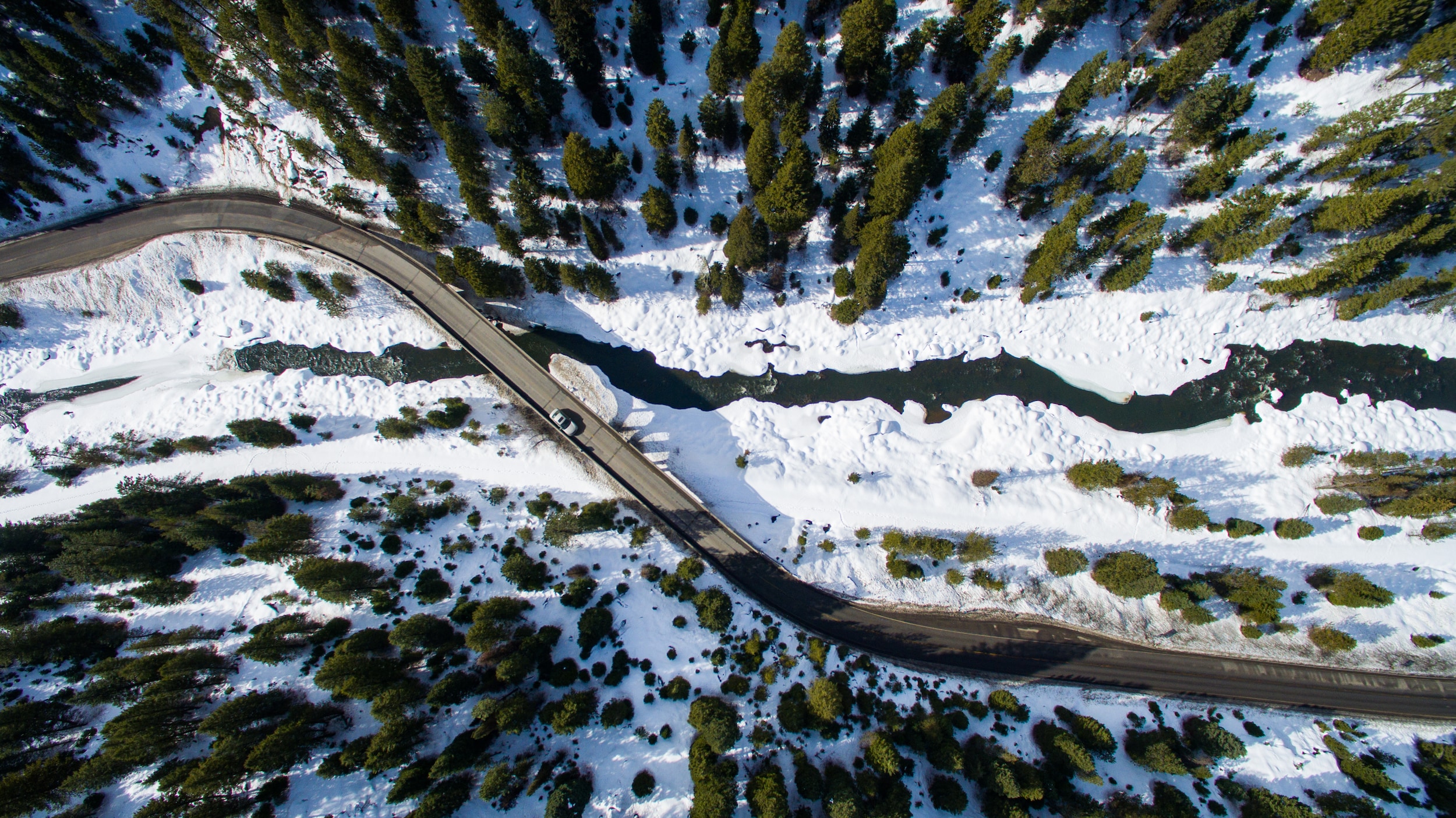 A snowy road winding across a frozen river.
