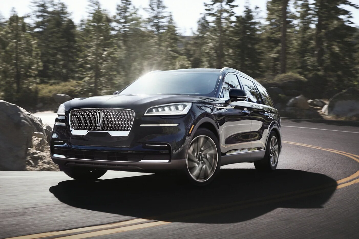 A 2022 Lincoln Aviator takes a curve on a mountain road