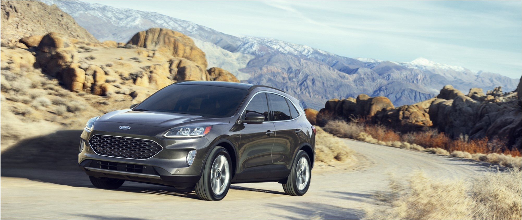 A blue 2020 Ford Escape driving in the desert mountains