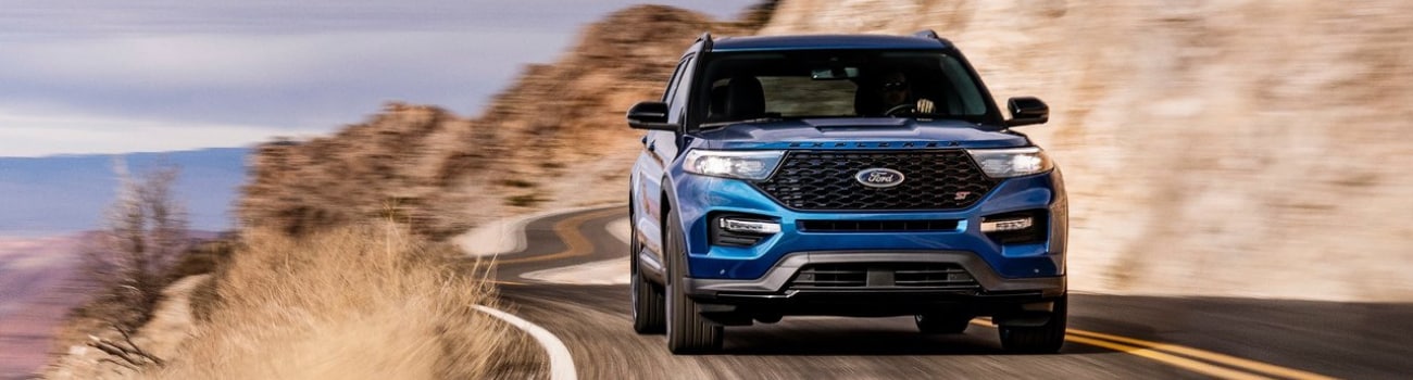 Exterior front view of a 2020 Ford Explorer driving around a curvy road on a mountain side
