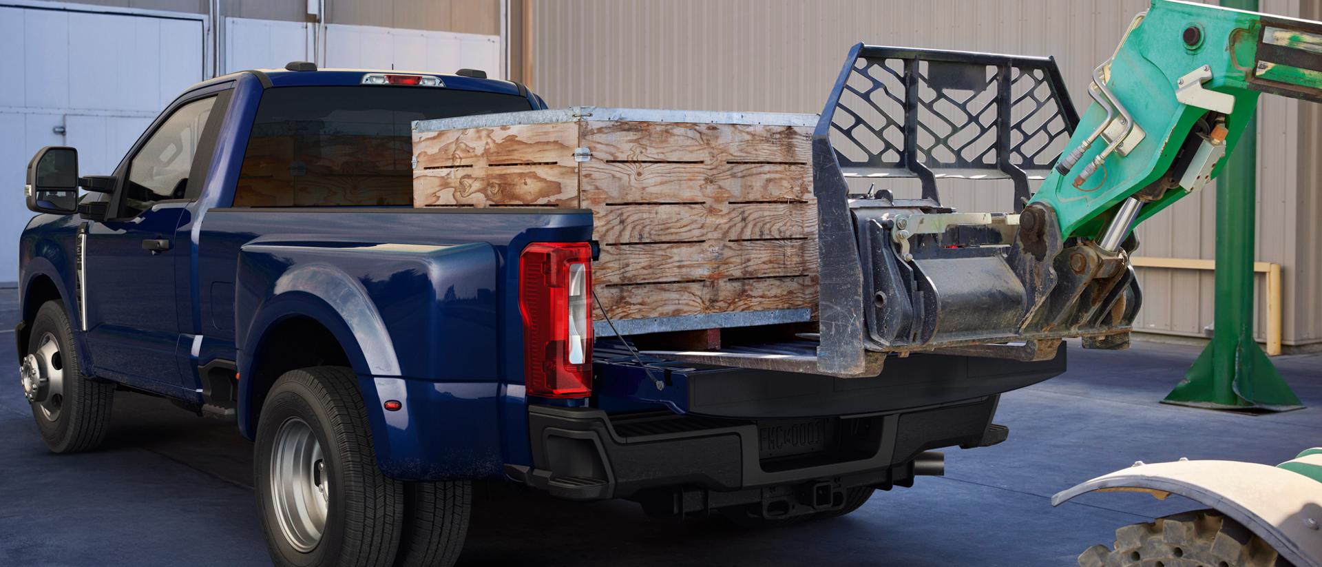 A heavy-duty Ford truck receiving a large construction materials pallet being loaded by a forklift