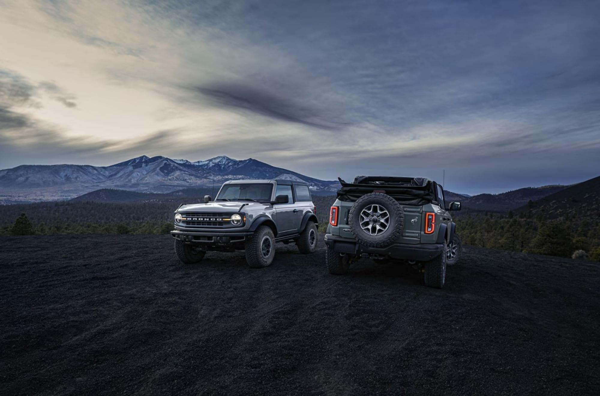Two Ford Broncos parked next to each other right after sunset