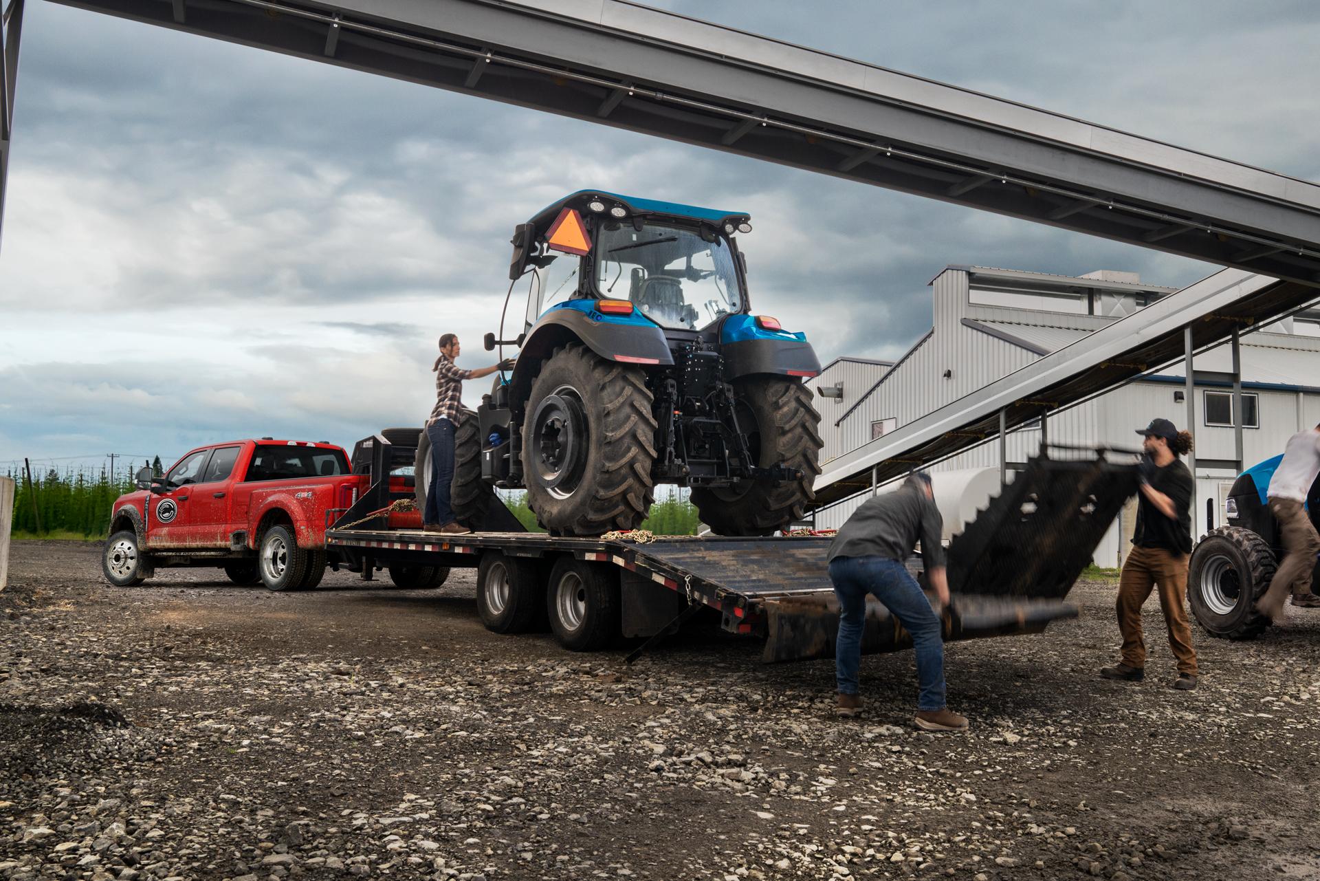 Red Ford Super Duty pulling a trailer as a tractor is loaded onto it
