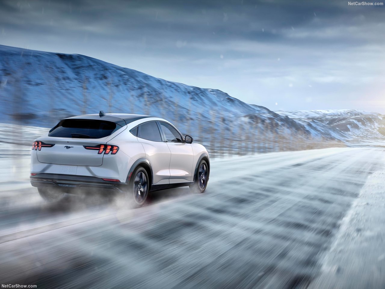 A Ford Mustang Mach-E Driving fast through a snow covered road.