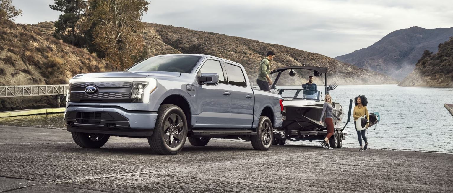 A Ford F-150 Lightning pulling a bout out of a lake from a boat ramp.