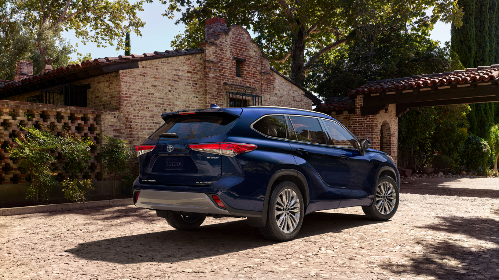 A view of the back of a dark blue 2023 Toyota Highlander Hybrid parked in a driveway