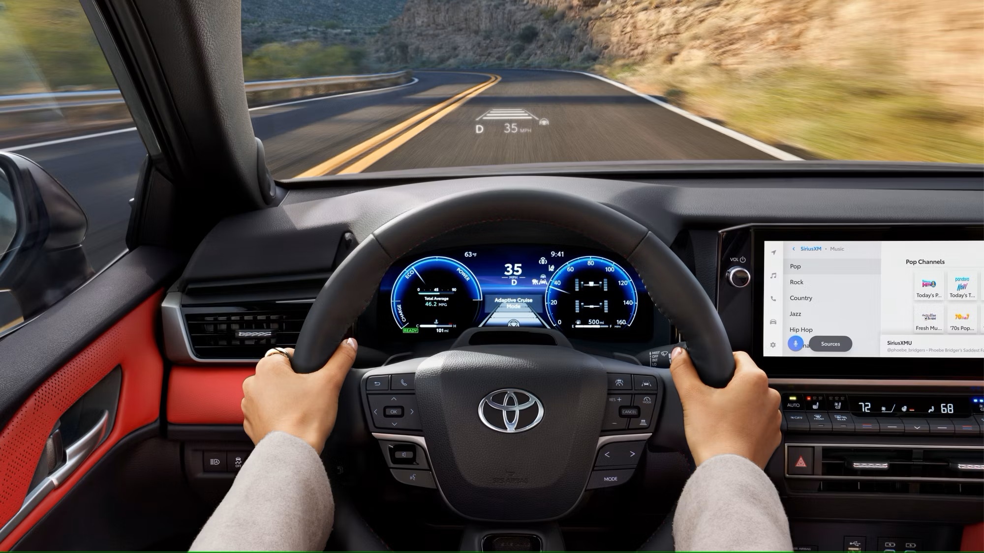 A 2025 Toyota Camry driving alongside a mountain road over a lake in a valley.
