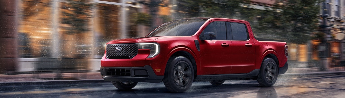 Red Ford Maverick XLT Truck driving in a city during a rain storm