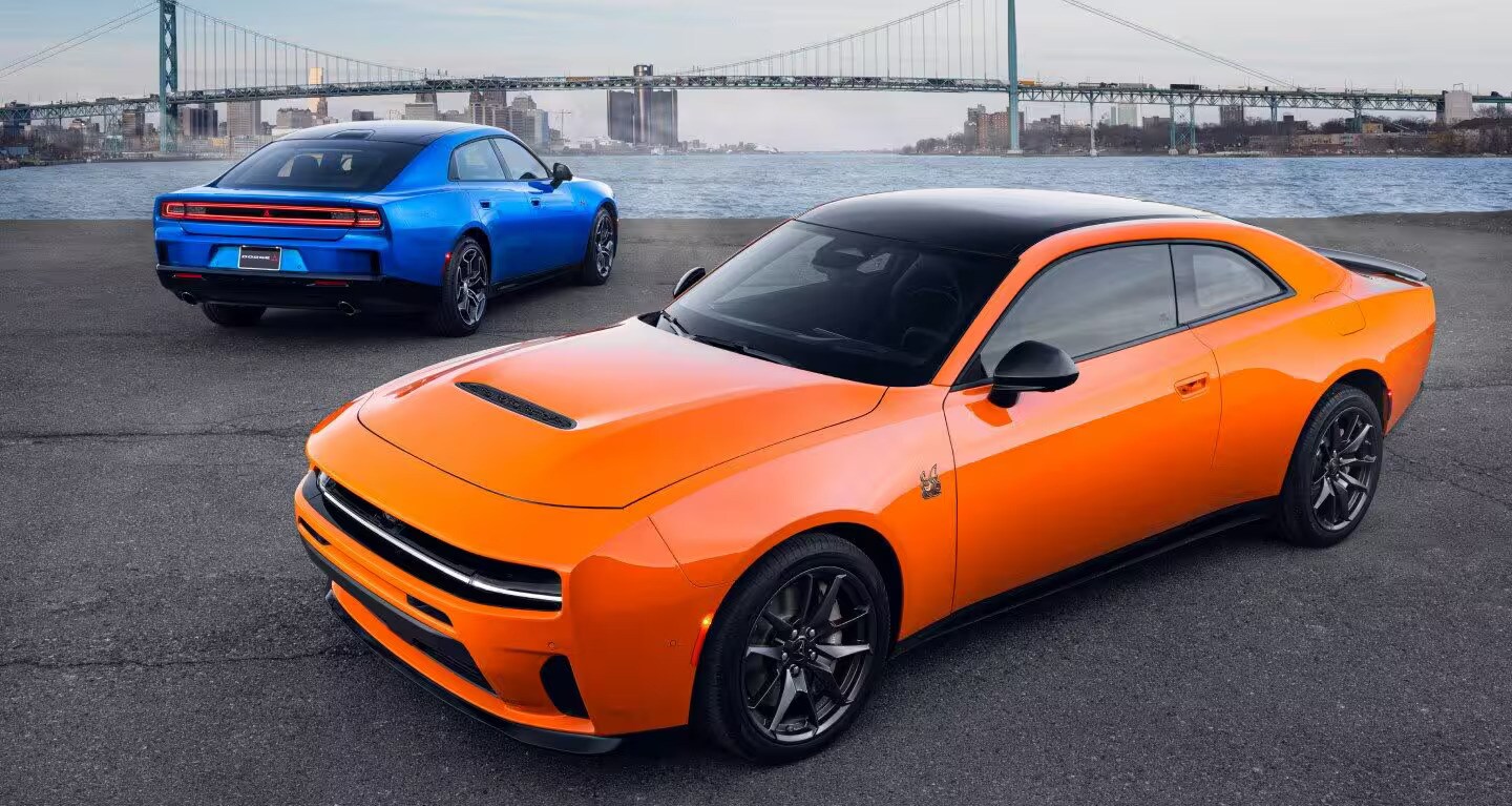  blue and orange 2026 dodge chargers with a city bridge in the distance