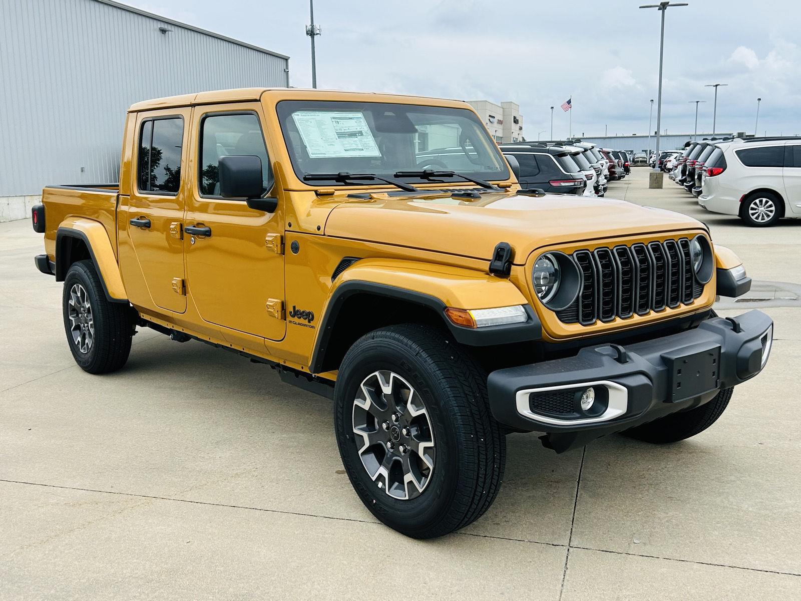 Orange Jeep Gladiator Sahara crew cab pickup with seven-slot grille and black fender flares, parked on a Pilson dealership lot