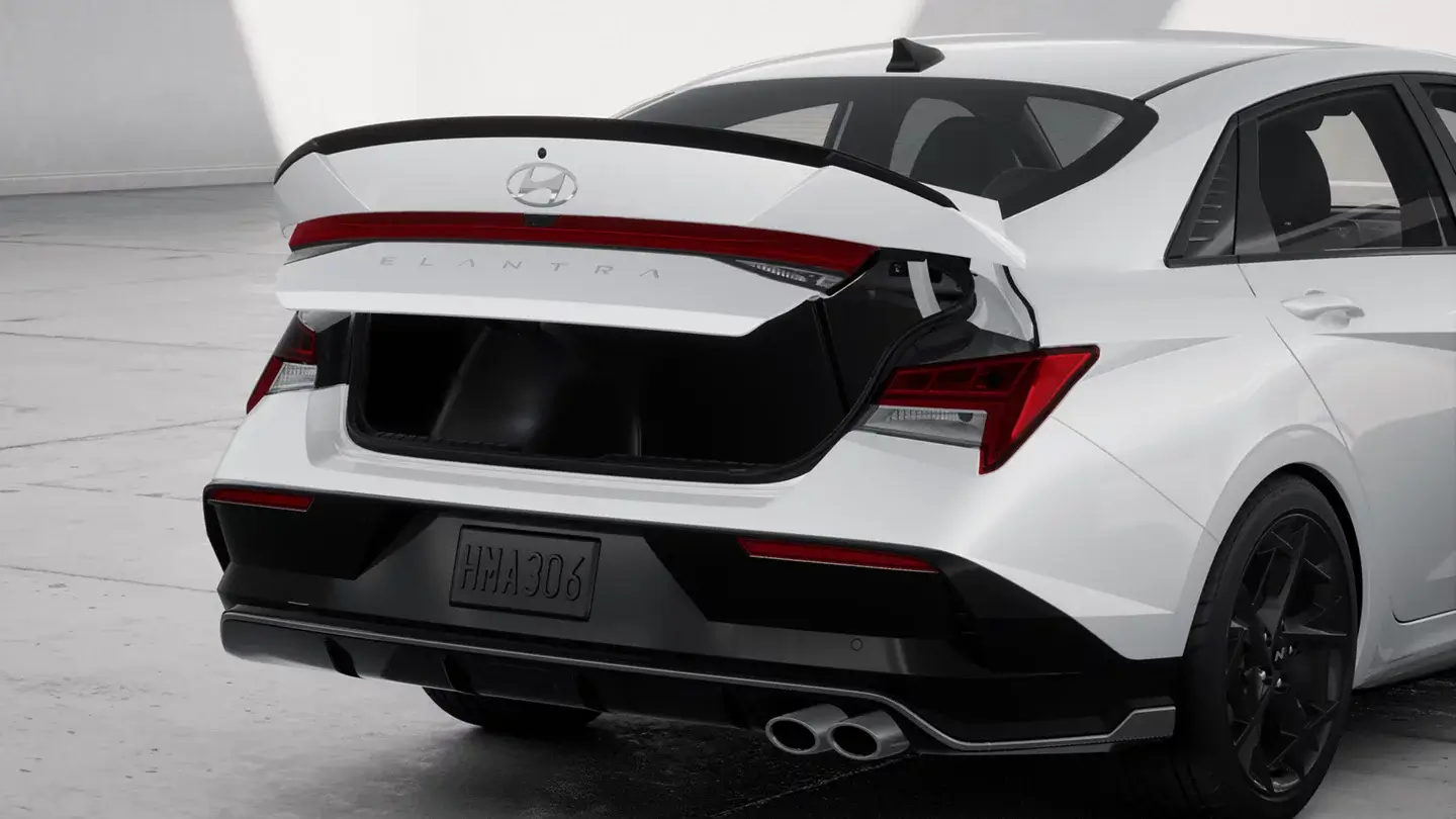 White Hyundai Elantra N with rear wing and open trunk, rear three-quarter view