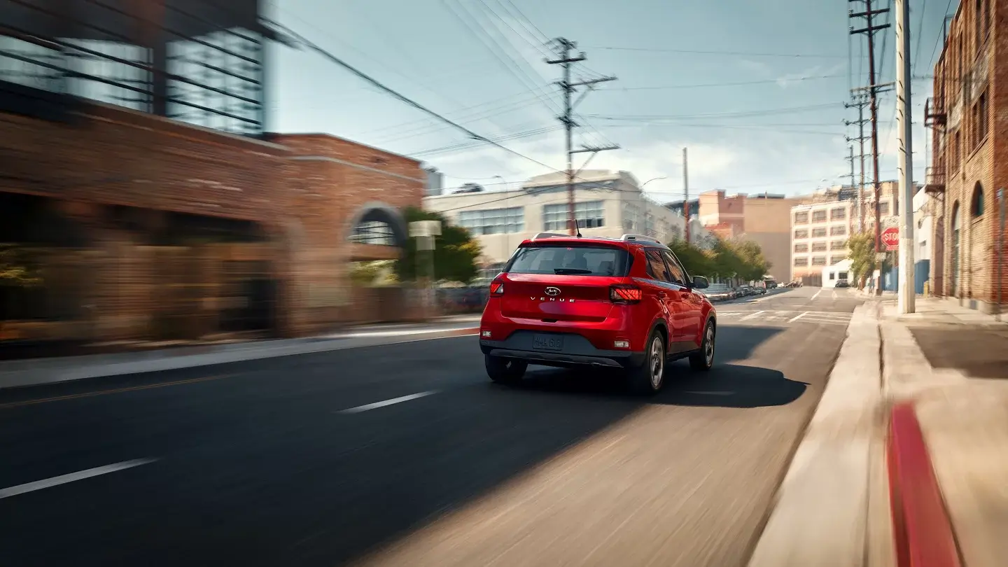 Hyundai Venue in Ultimate Red, rear three-quarter view showing taillights and roof spoiler