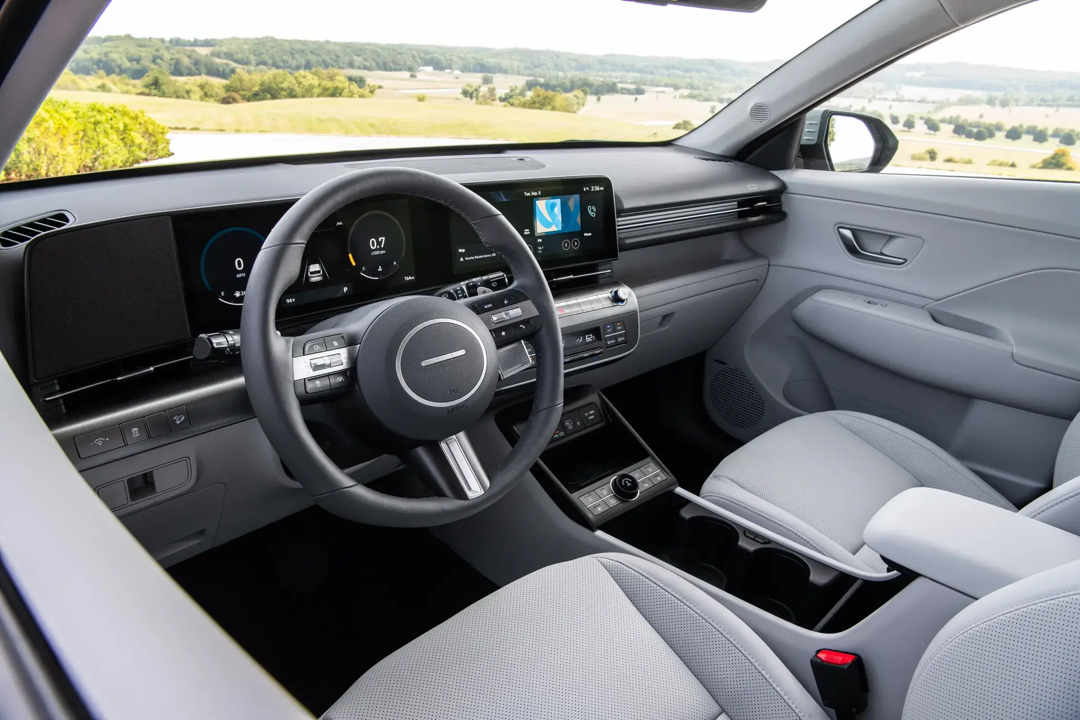 Hyundai Kona interior photographed from outside the driver side window, showing the steering wheel and front cabin