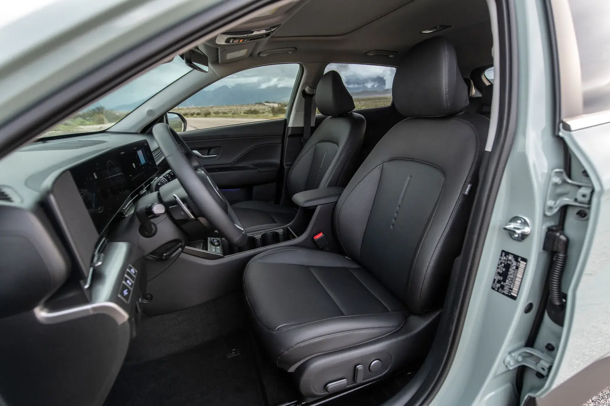 Hyundai Kona Limited interior seen through the open driver door, showing the seat, dashboard and door panel