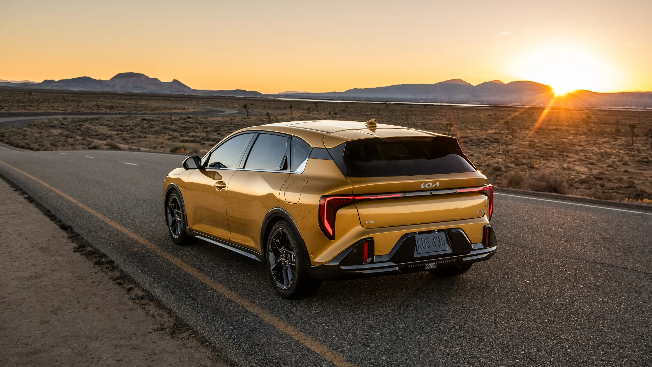 Rear view of 2026 Kia K4 Hatchback on open desert road with sunset lighting