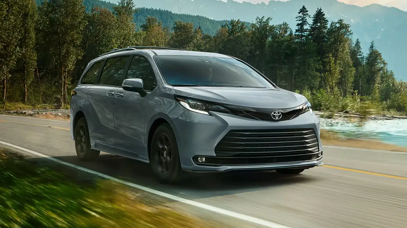 Toyota Sienna minivan photographed from the front three-quarter angle showing grille and LED headlights