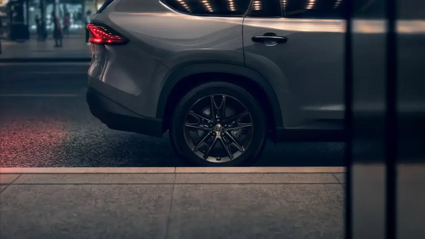 Toyota Grand Highlander Hybrid Nightshade in Cement viewed from the rear quarter showing black 20-inch alloy wheels