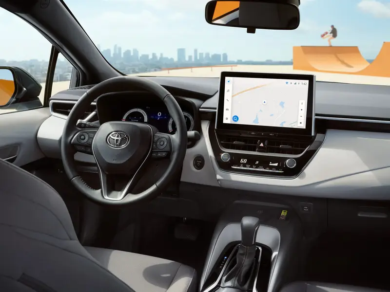 Toyota Corolla cabin viewed from the rear seats showing the touchscreen and steering wheel